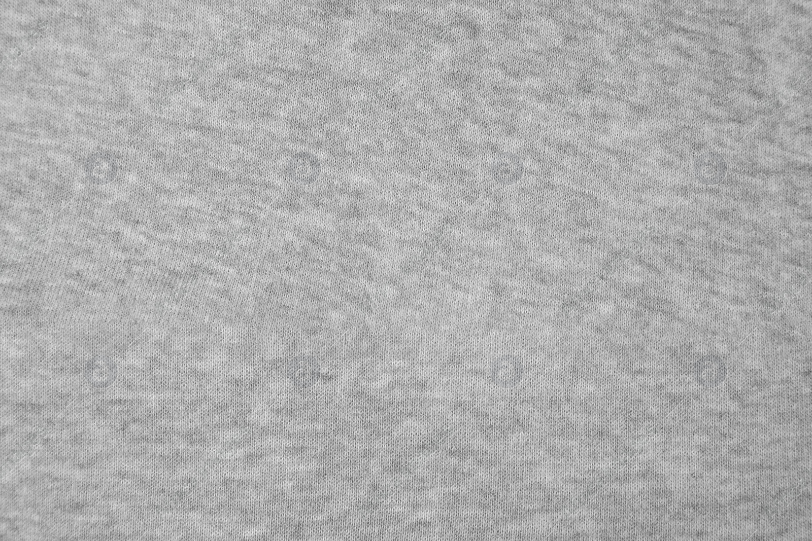 Photo of Light grey cloth with lint as background, top view. Before using fabric shaver