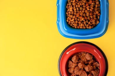 Wet and dry pet food in feeding bowls on yellow background, flat lay. Space for text