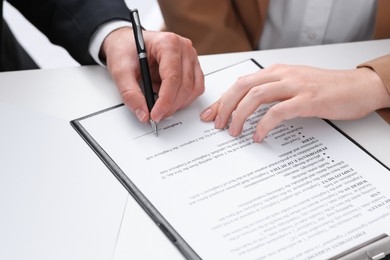 Photo of Businesspeople signing contract at white table, closeup of hands