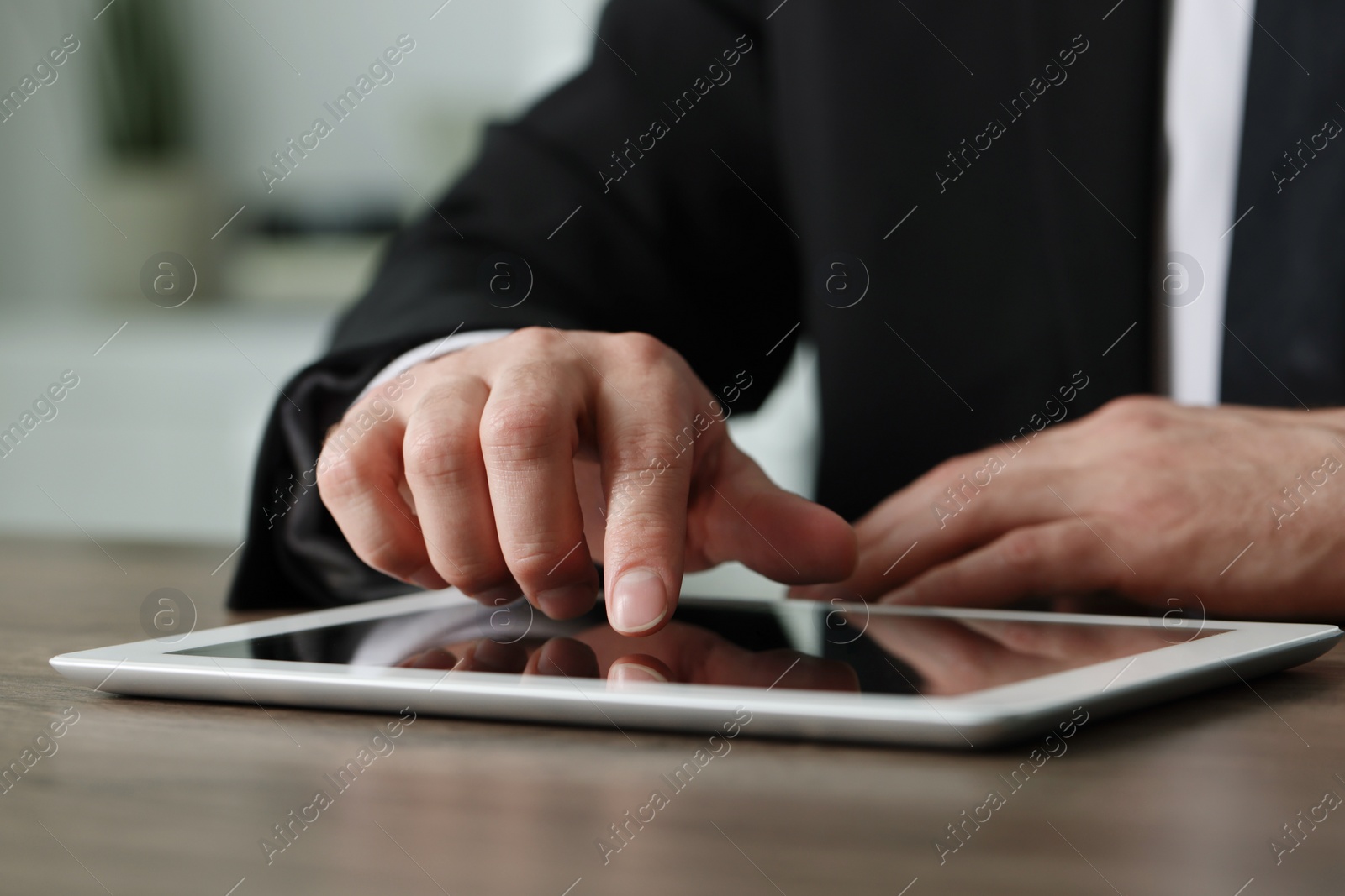 Photo of Closeup view of man using new tablet at wooden desk indoors