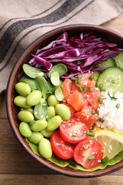 Poke bowl with salmon, edamame beans and vegetables on wooden table, top view