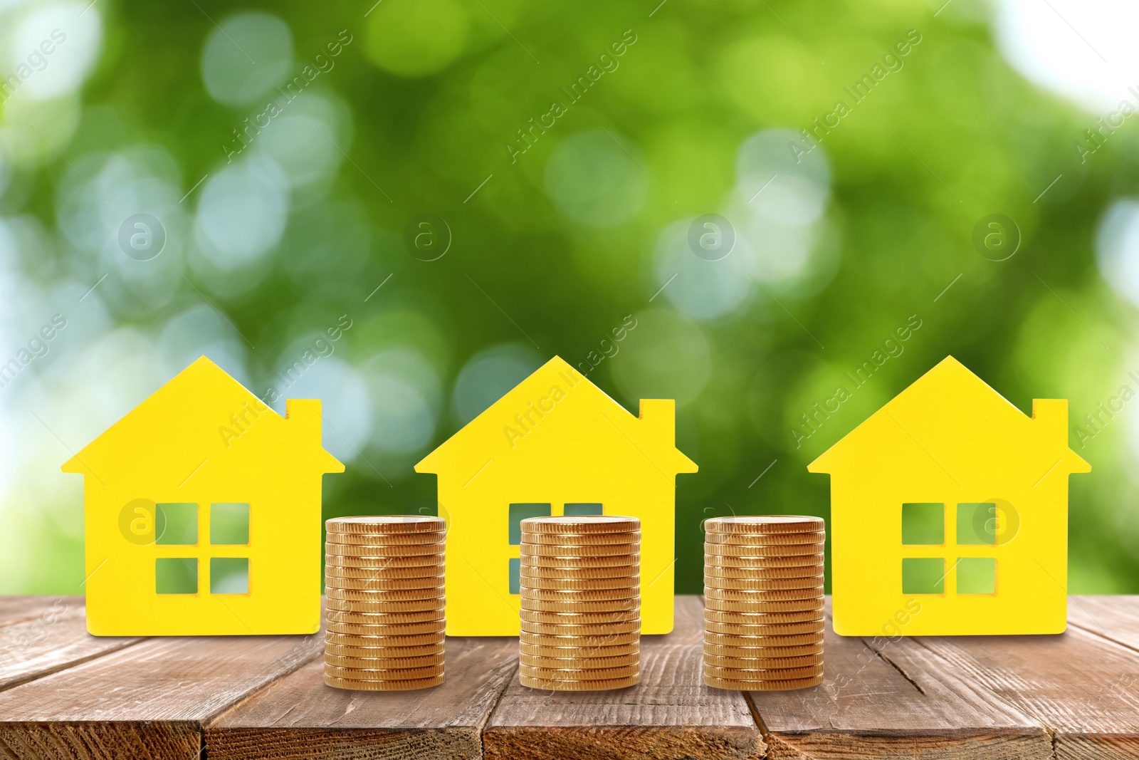 Image of Real estate investing. House models and coins on wooden table