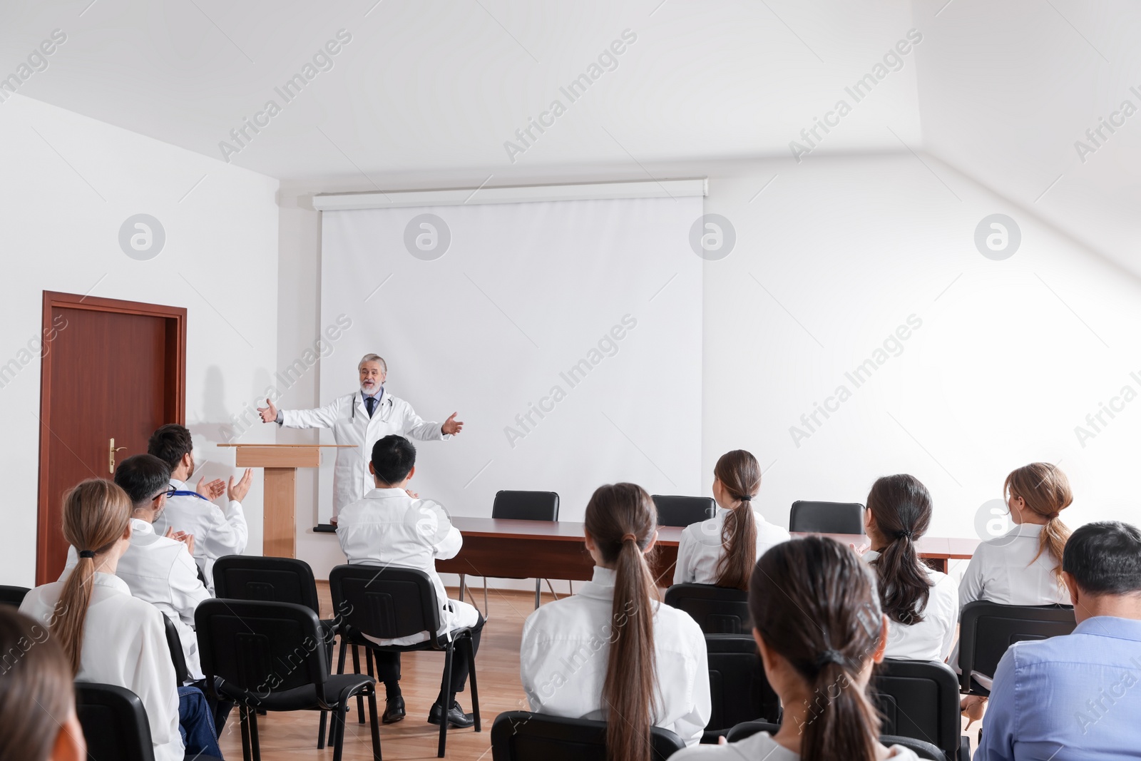 Photo of Senior doctor giving lecture to audience during medical conference in meeting room