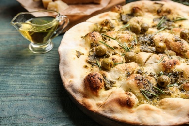 Photo of Traditional Italian focaccia bread with guacamole, olives and rosemary on blue wooden table, closeup