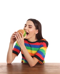 Photo of Young woman eating tasty burger at table on white background