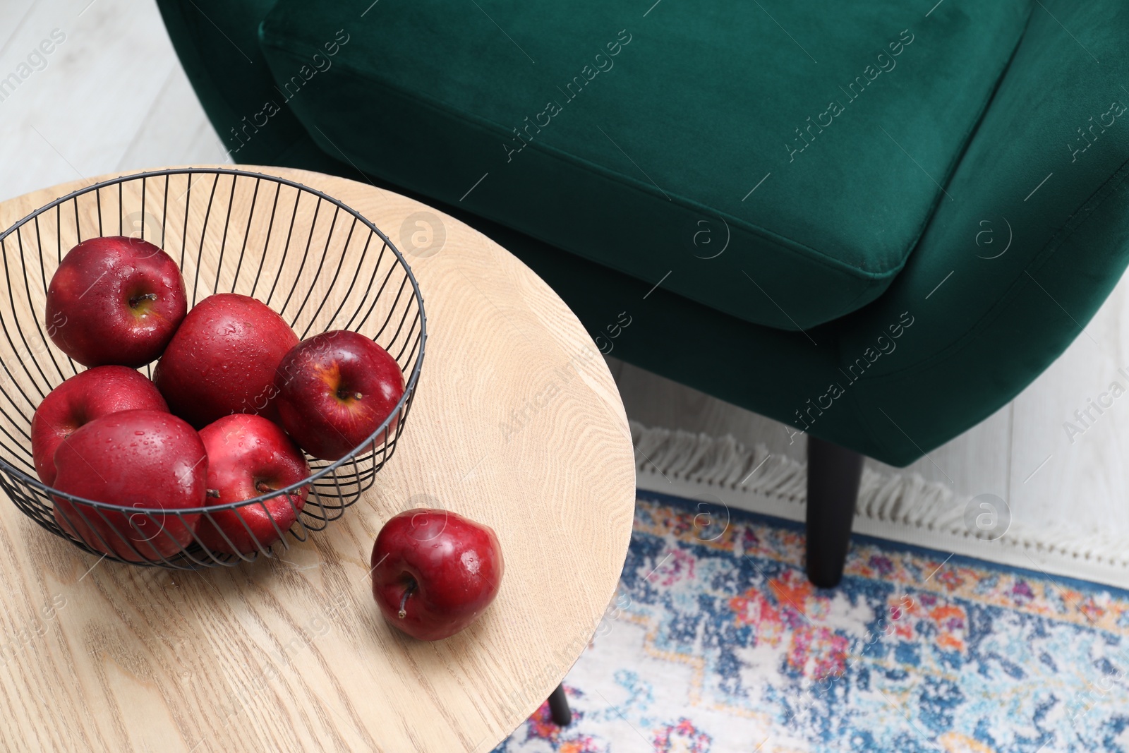 Photo of Red apples on side table near armchair in room, above view