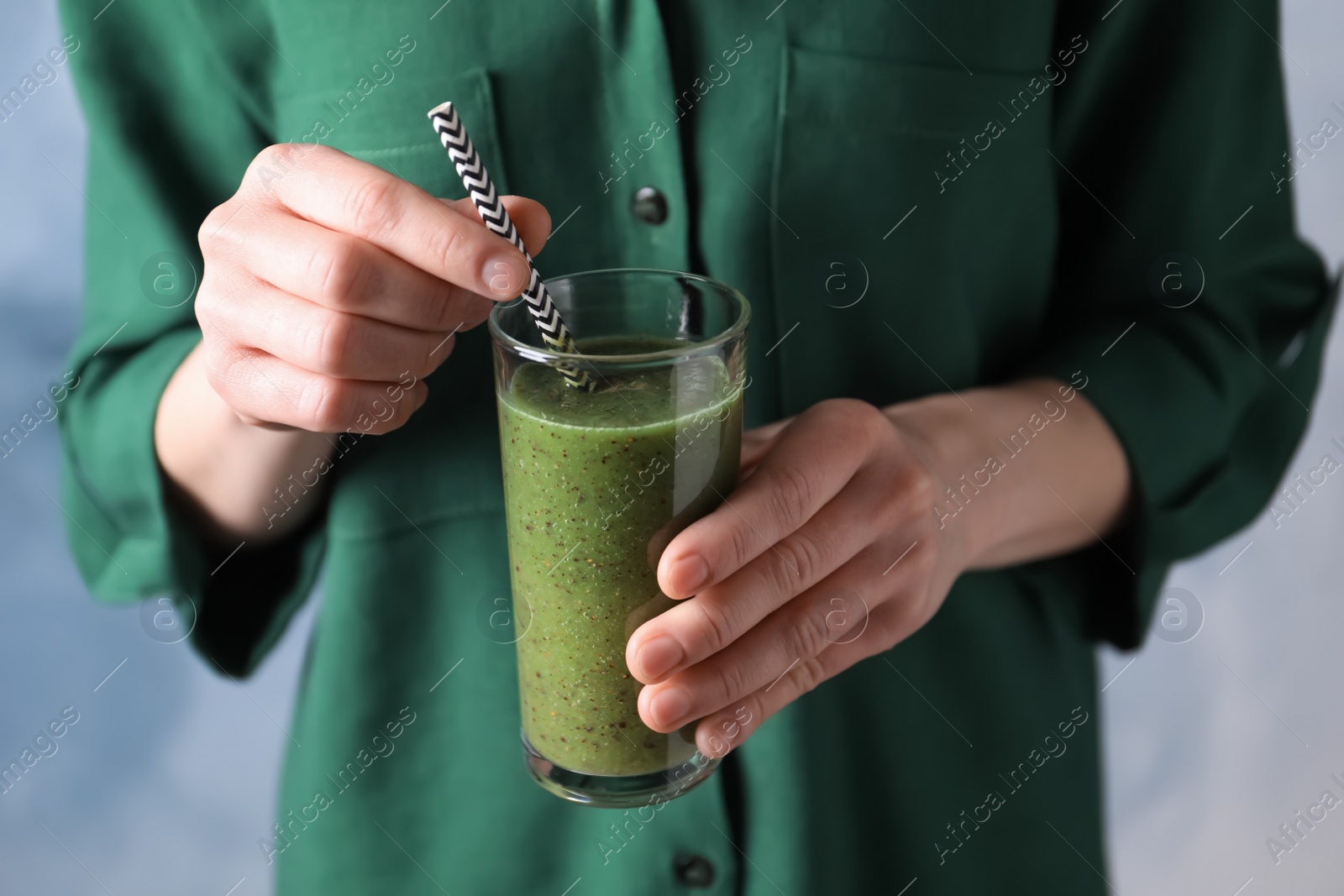 Photo of Woman with delicious kiwi smoothie on blue background, closeup