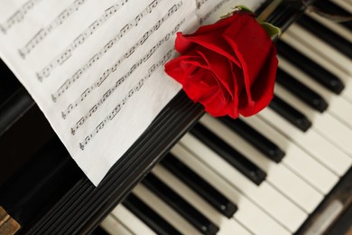 Photo of Beautiful rose and musical notes on piano, above view