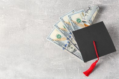Photo of Scholarship concept. Graduation cap and banknotes on light grey table, flat lay with space for text