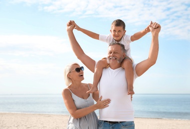 Photo of Little boy and happy grandparents spending time together on sea beach
