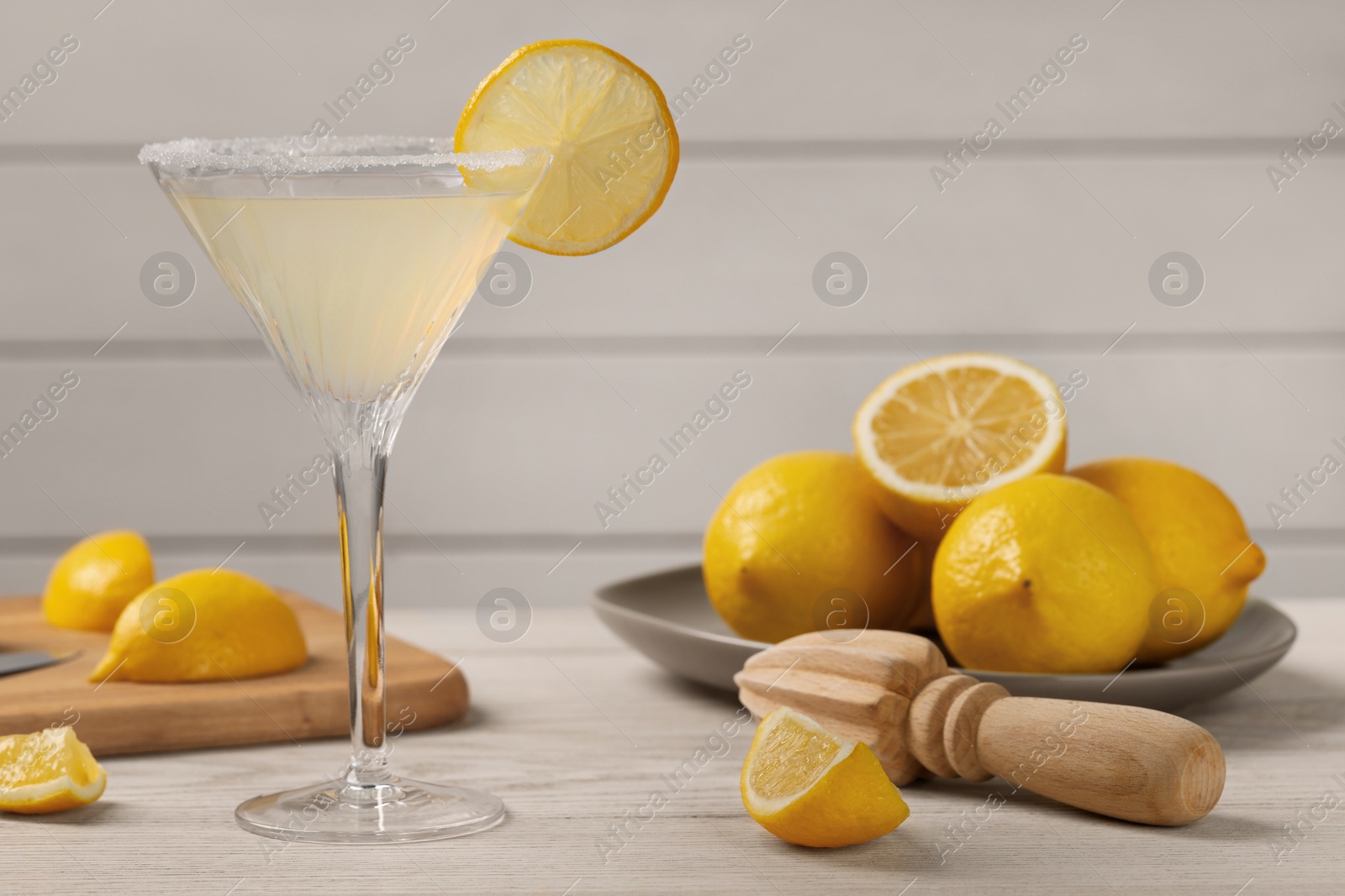Photo of Lemon Martini cocktail and fresh fruits on white wooden table, space for text