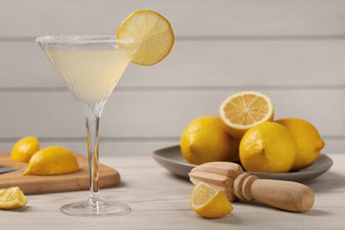 Photo of Lemon Martini cocktail and fresh fruits on white wooden table, space for text