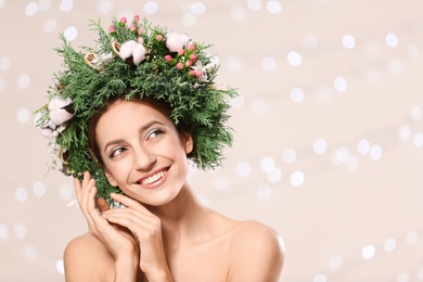 Happy young woman wearing wreath against blurred lights. Space for text