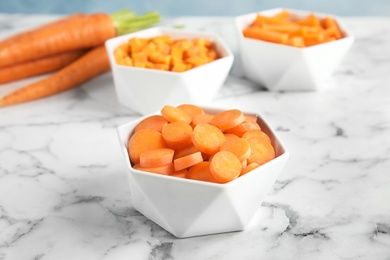 Bowl with cut ripe carrot on table