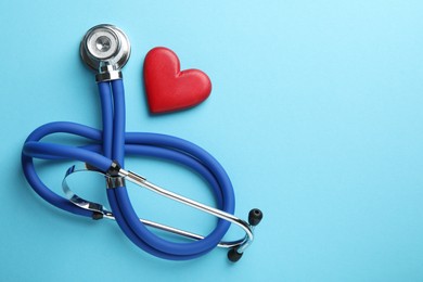 Stethoscope and red heart on light blue background, top view. Space for text