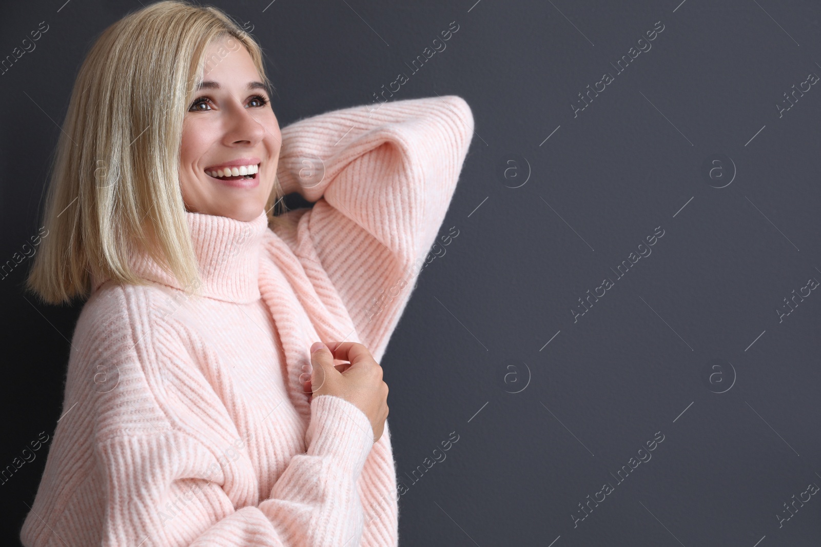 Photo of Happy woman in stylish sweater on black background. Space for text