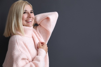 Photo of Happy woman in stylish sweater on black background. Space for text