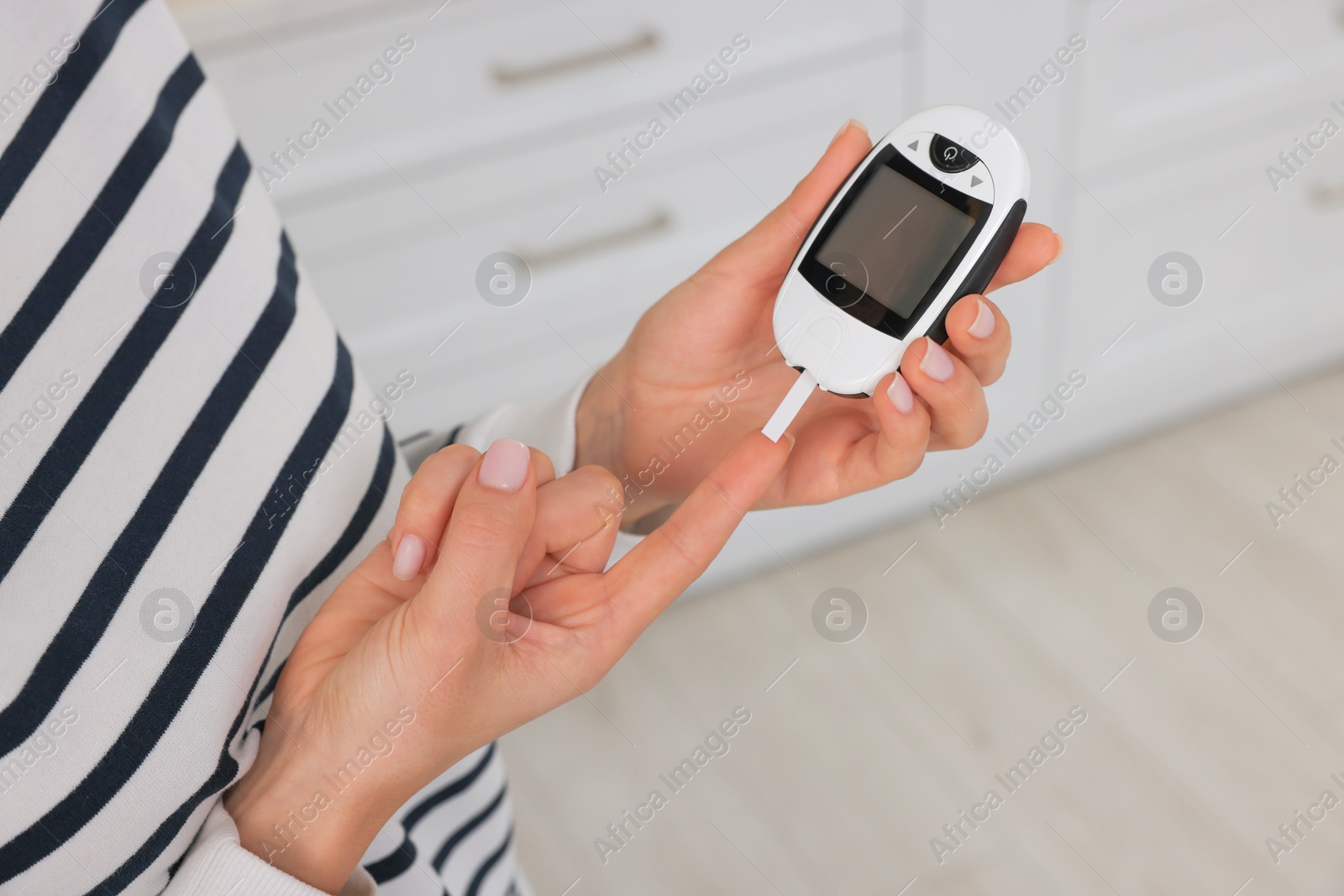 Photo of Diabetes. Woman checking blood sugar level with glucometer in kitchen, closeup
