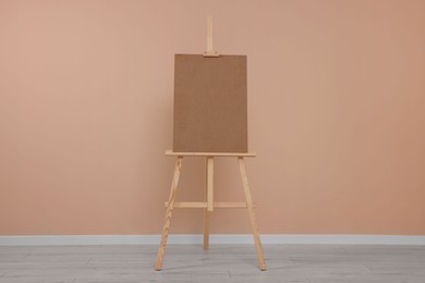 Photo of Wooden easel with blank board near beige wall indoors