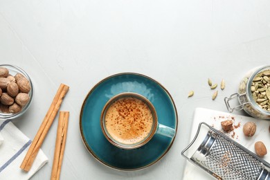 Photo of Coffee with nutmegs, spices and grater on white table, flat lay. Space for text