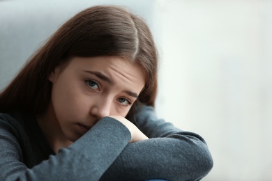 Photo of Upset teenage girl on blurred background. Space for text