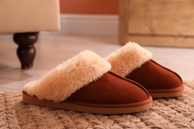 Brown warm slippers on floor in room