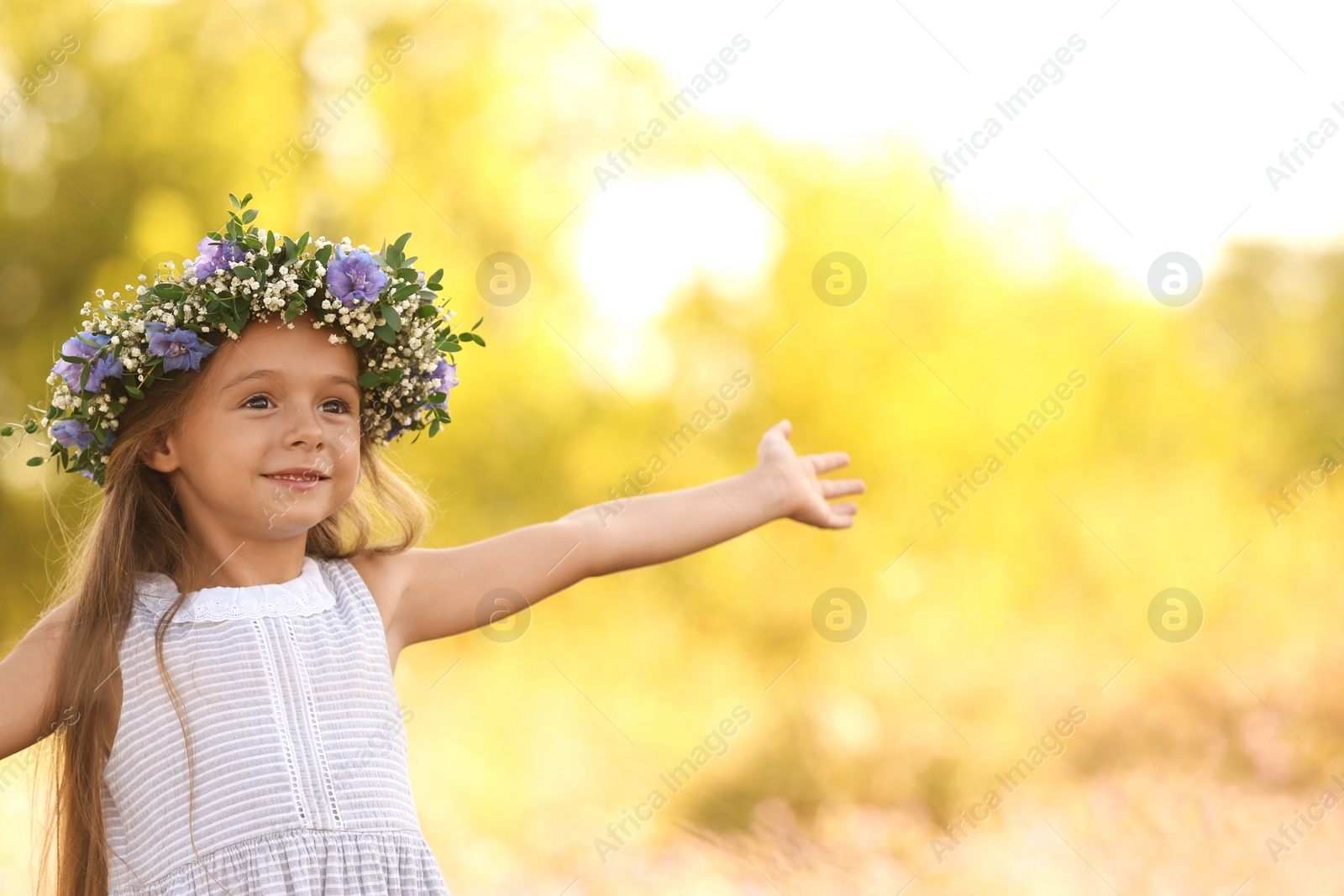 Photo of Cute little girl wearing flower wreath outdoors. Child spending time in nature