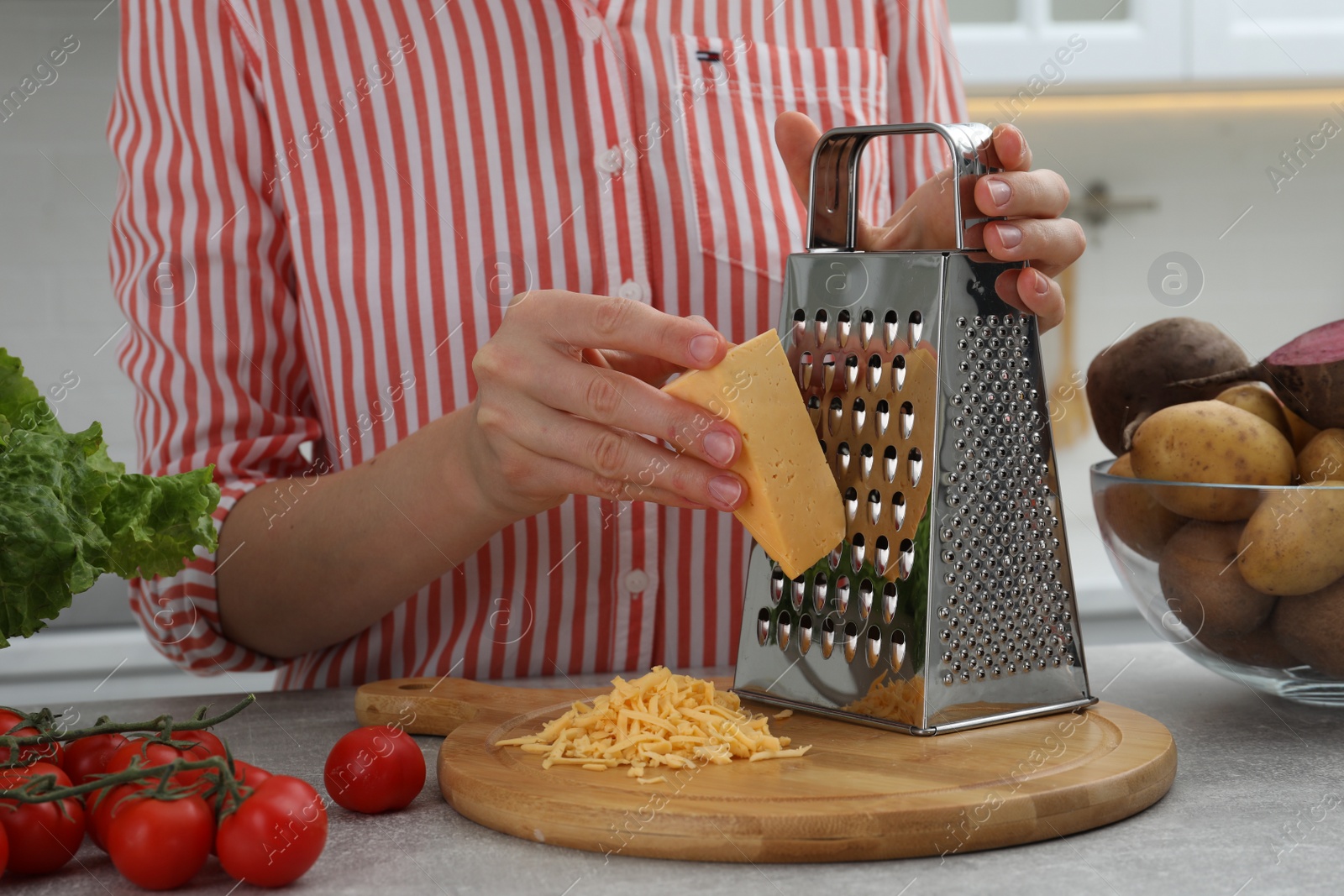 Photo of Woman grating cheese at kitchen table, closeup