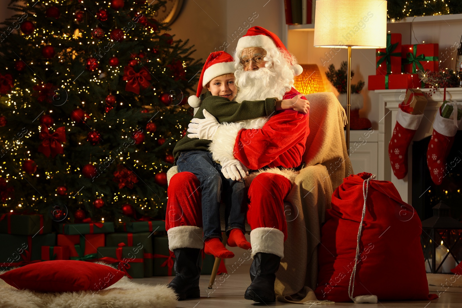 Photo of Merry Christmas. Little boy hugging Santa Claus at home