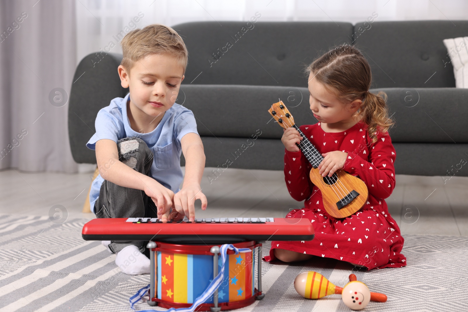 Photo of Little children playing toy musical instruments at home