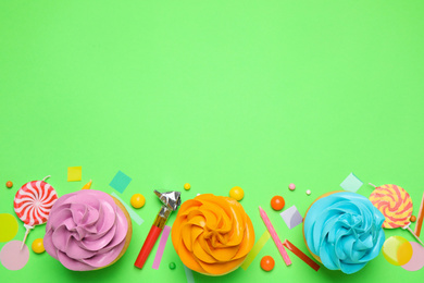Photo of Flat lay composition with colorful birthday cupcakes on green background. Space for text