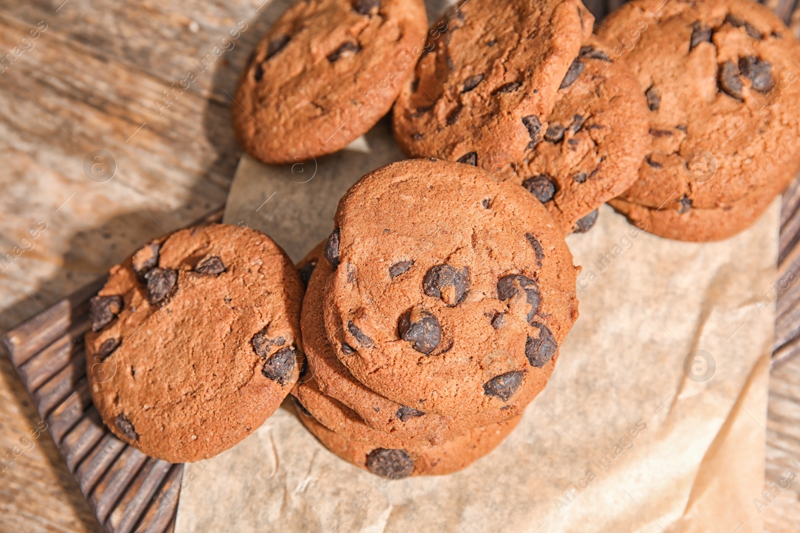 Photo of Board with chocolate chip cookies on wooden table