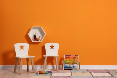 Photo of Beautiful children's room with bright orange wall and furniture, space for text. Interior design