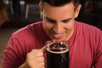 Photo of Man drinking dark beer from glass outdoors, closeup