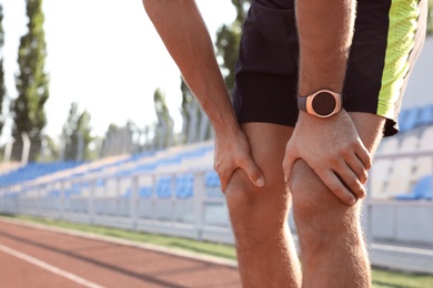 Photo of Man with fitness tracker after training at stadium, closeup