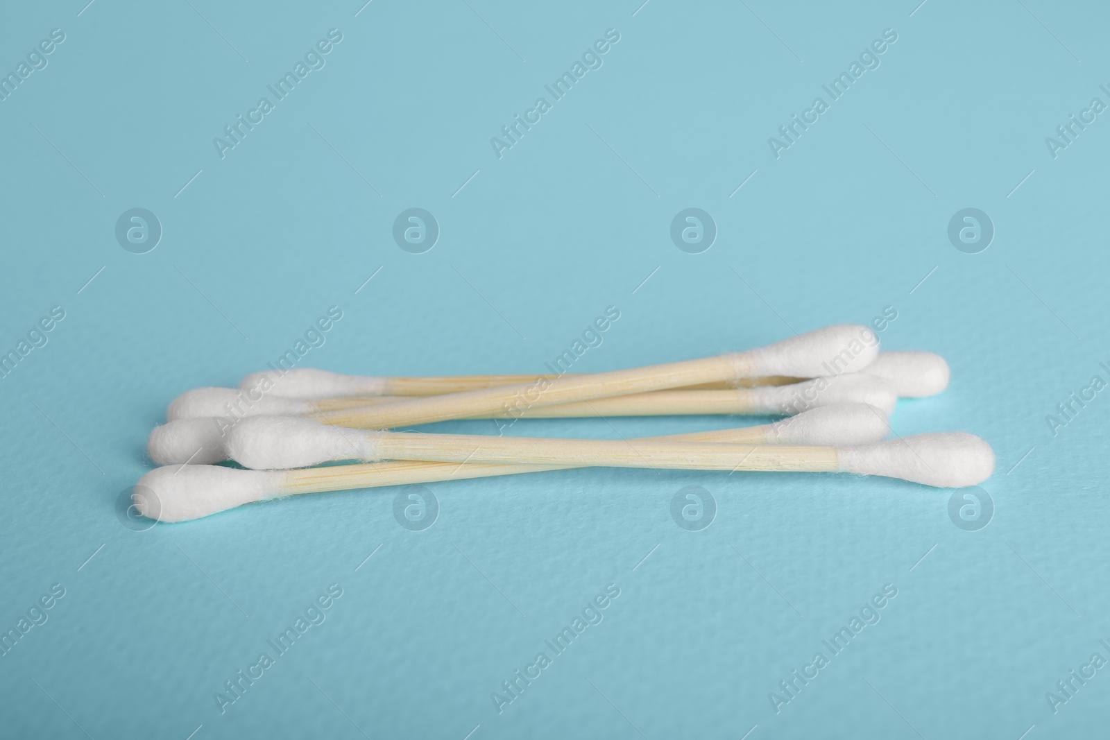 Photo of Wooden cotton buds on light blue background