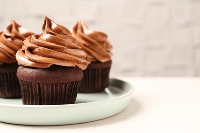 Delicious fresh chocolate cupcakes with cream on white table, closeup