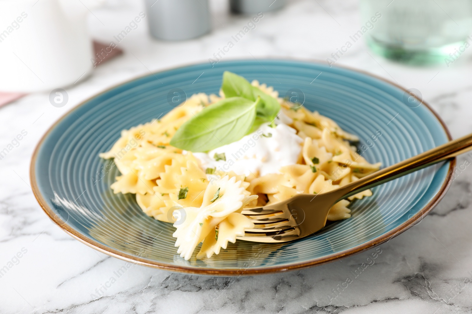 Photo of Tasty pasta with sauce and basil on white marble table, closeup