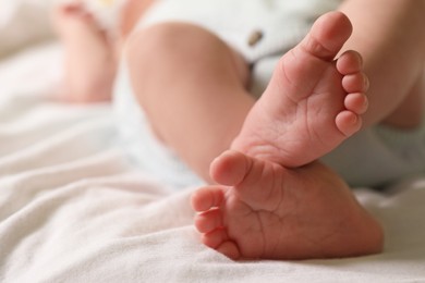 Photo of Cute newborn baby lying on bed, closeup of legs. Space for text