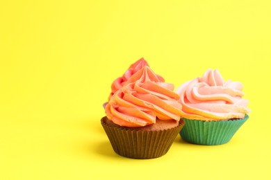 Photo of Delicious cupcakes with bright cream on yellow background