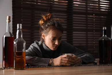 Photo of Alcohol addiction. Woman chained with glass of liquor at wooden table in room