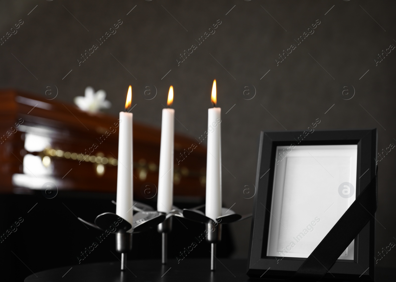 Photo of Black photo frame with burning candles on table in funeral home