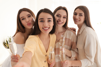 Photo of Beautiful young ladies with champagne taking selfie indoors. Woman's Day