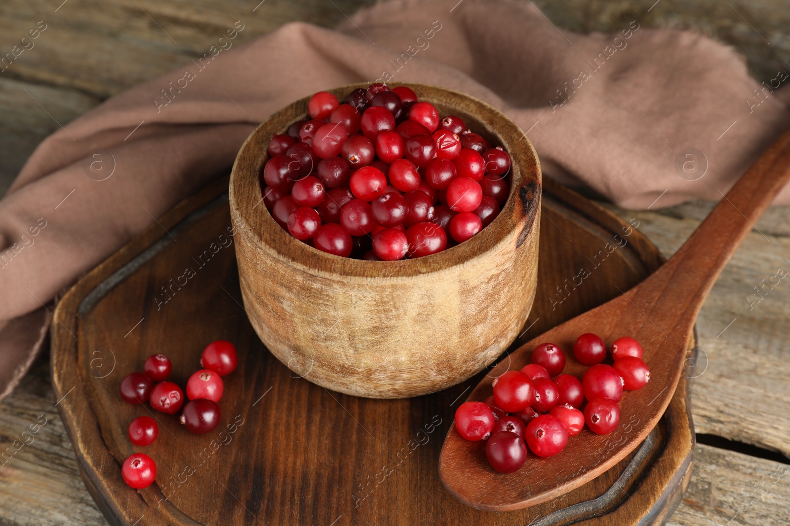 Photo of Cranberries in bowl and spoon on wooden table