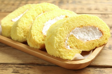 Photo of Delicious cake roll with cream filling on wooden table, closeup