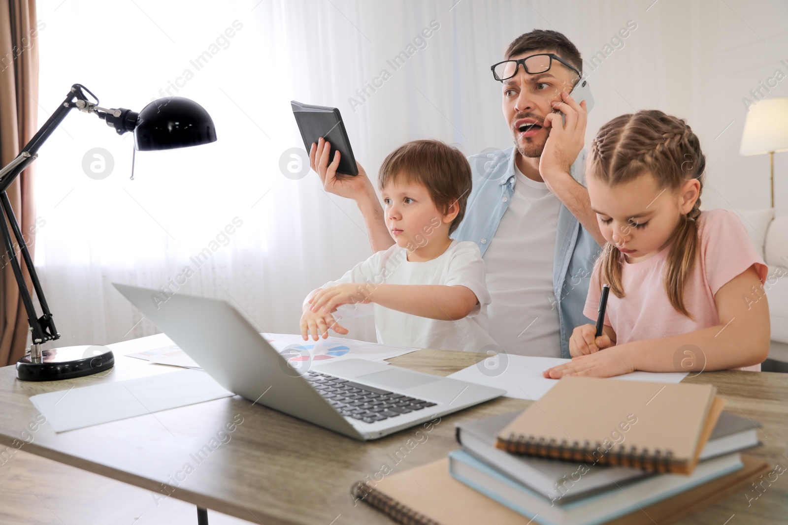 Photo of Overwhelmed man combining parenting and work at home