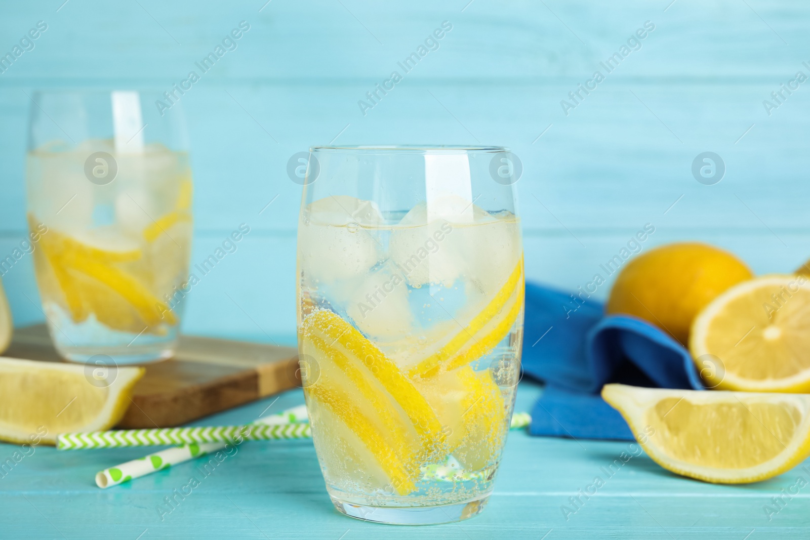 Photo of Soda water with lemon slices and ice cubes on light blue wooden table