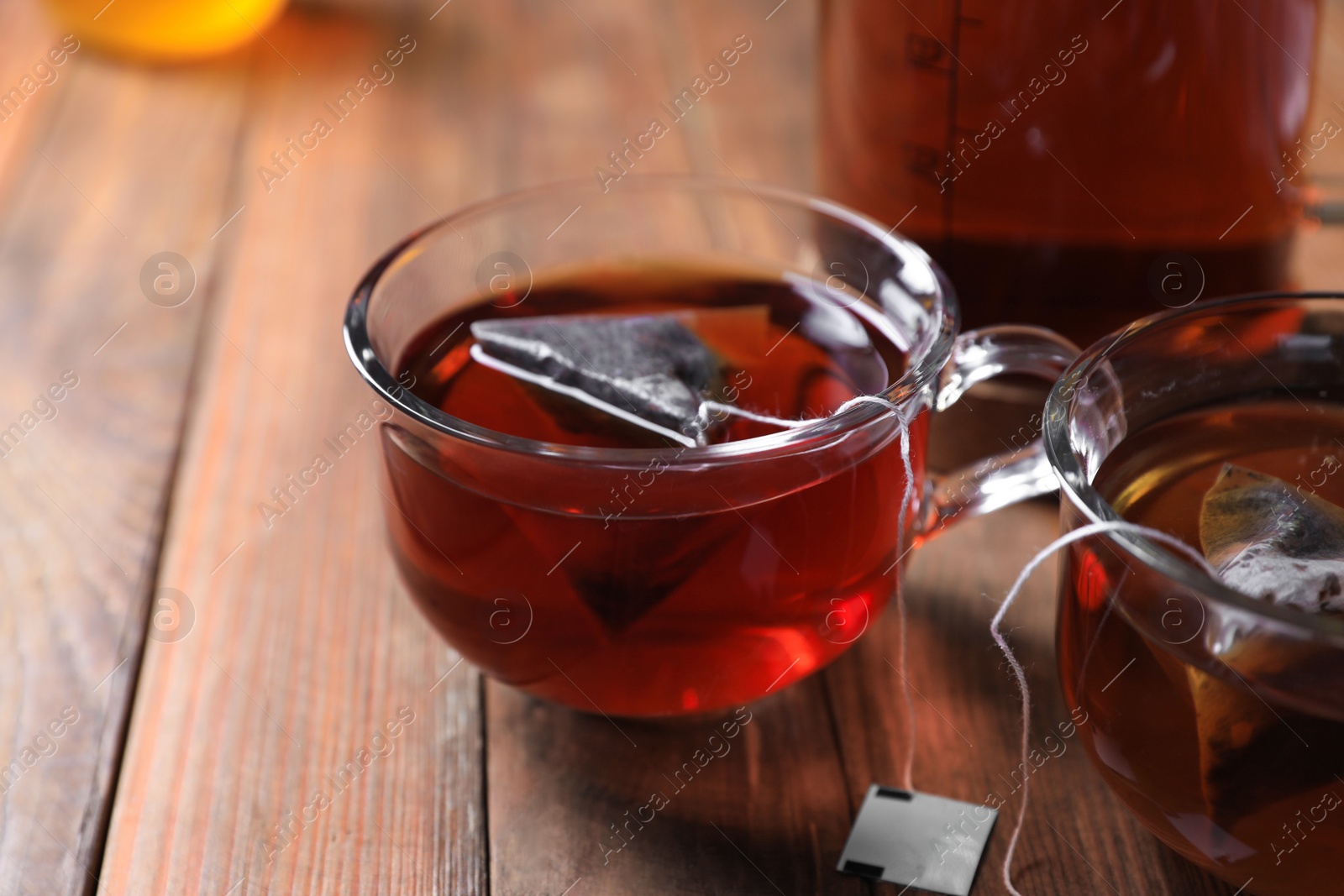 Photo of Tea bag in cup on wooden table, closeup