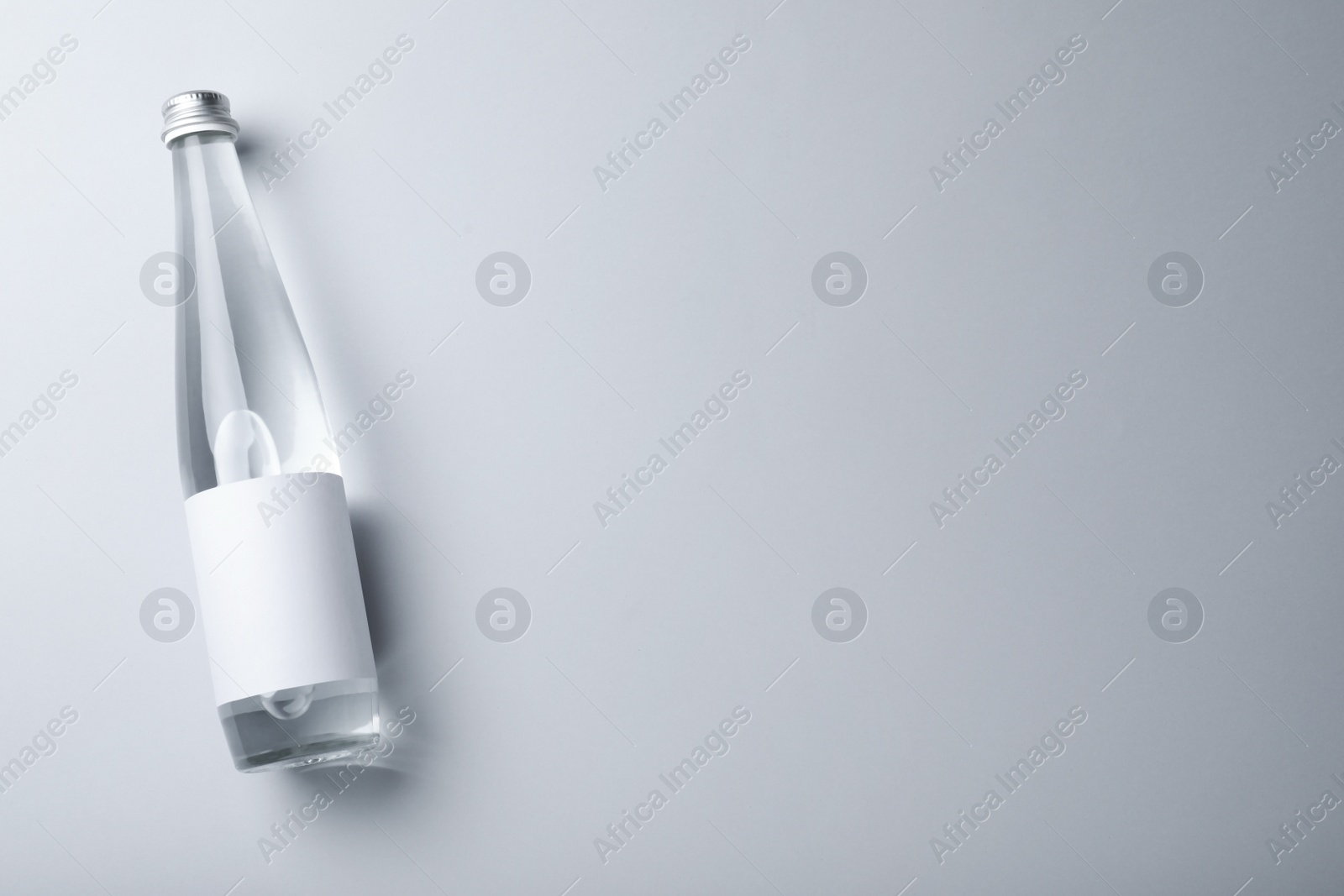 Photo of Glass bottle with soda water on light background, top view. Space for text