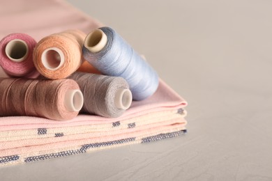 Photo of Set of color sewing threads on light grey table, space for text